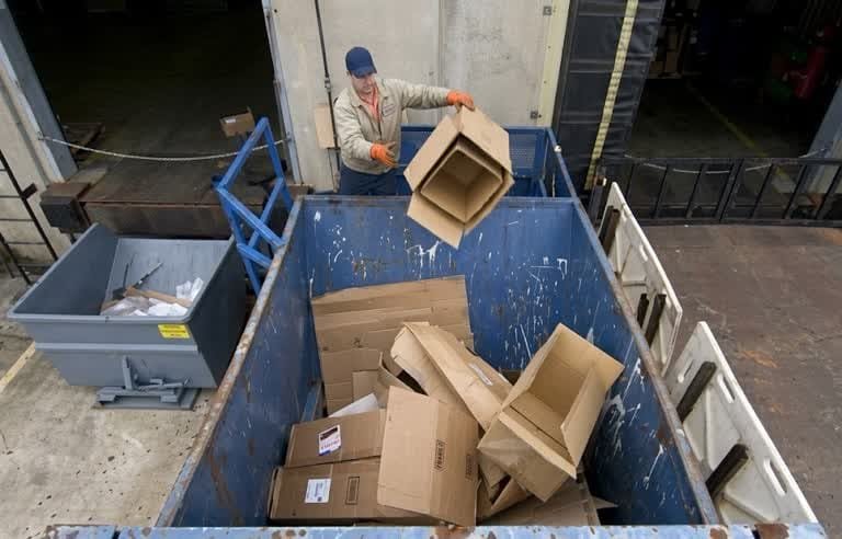 Operario en labor de recolección de residuos industriales en Usaquén clasificando cartón.
