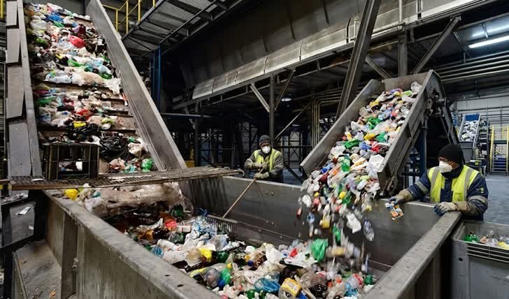 Operarios con mascarillas y chalecos reflectantes supervisan la separación automática en una planta de gestión de residuos industriales en Kennedy.