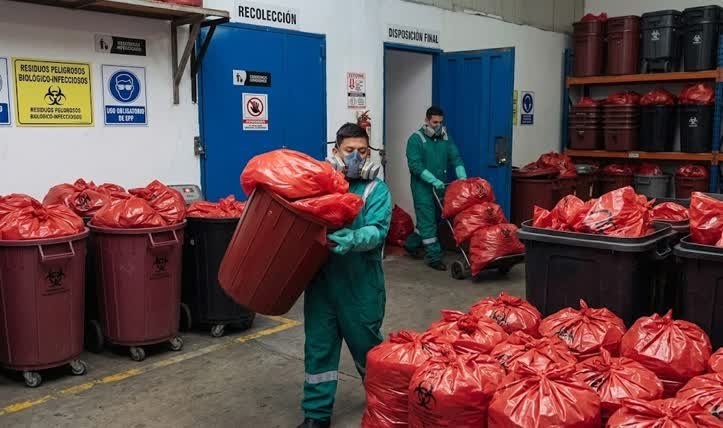 Personal técnico realizando la gestión de residuos industriales en Tunjuelito mediante el manejo de desechos biológicos en bolsas rojas y contenedores especializados.